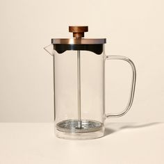 a glass french press coffee maker with a wooden lid