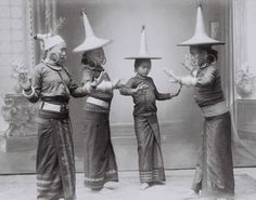 three women in costumes with hats on their heads and arms, one holding her hands out to the other