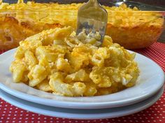 a fork is stuck into some macaroni and cheese casserole on a plate