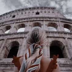 a woman standing in front of the colossion with her hair blowing in the wind