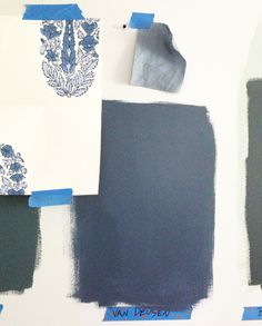 several different shades of blue and green paint on a wall with some white paper taped to it