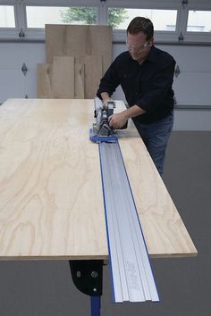 a man sanding plywood on top of a table with a power drill attachment