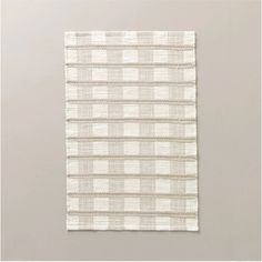 a piece of cloth hanging on the wall in front of a gray background with white squares