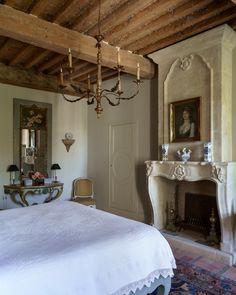 a bedroom with a bed, fireplace and chandelier