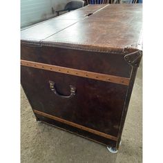 an old trunk is sitting on the ground in front of a table with chairs behind it