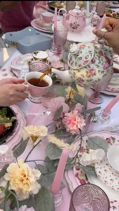 people are sitting at a table with pink and white plates, cups and saucers