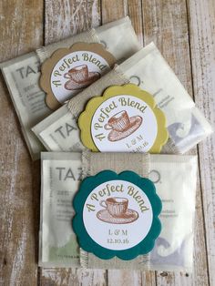 three tea bags with labels on them sitting next to each other in front of a wooden table