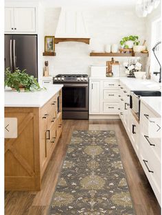 a kitchen with white cabinets and wooden floors, an area rug is on the floor