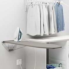 an ironing board sitting on top of a white shelf next to clothes and iron