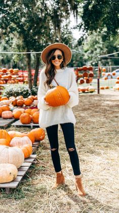 a woman standing in front of pumpkins