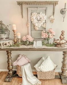 a table with flowers and candles on it in front of a birdcage hanging from the wall