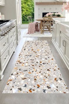 a kitchen with white cabinets and an area rug on the floor in front of it