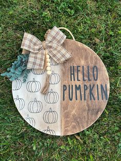 a wooden sign that says hello pumpkin on it with a bow around the front and side