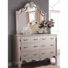 a dresser with a mirror and flowers on it