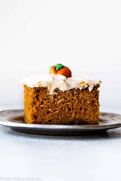 a piece of carrot cake with white frosting and an orange on top is sitting on a plate