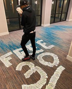 a man standing on top of a floor covered in paper mache letters and money