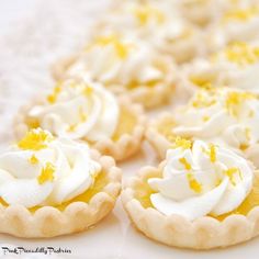 lemon meringue tarts with whipped cream toppings on a white tablecloth