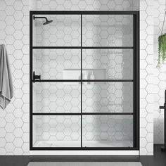 a white tiled bathroom with black accents and hexagonal tiles on the wall, along with a glass shower door