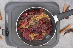 a frying pan filled with food on top of a counter next to some spices