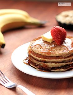 a stack of pancakes with syrup and a strawberry on top