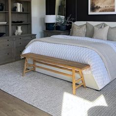 a bedroom with a bed, dressers and a bench in front of the bed