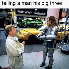 a man in armor talking to a woman on the street