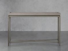 a metal table with a white top on a concrete floor in front of a gray wall