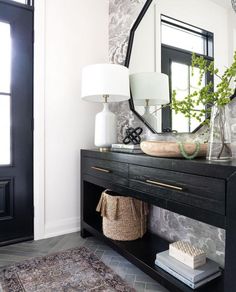 a black and white entryway with a mirror, vase on the side table and a rug