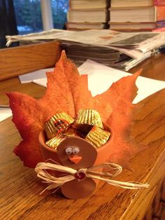 a leaf shaped container filled with candy sitting on top of a wooden table