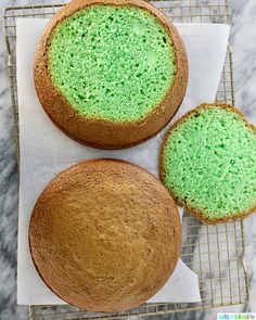 two cakes with green frosting sitting on top of a cooling rack