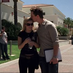 a man and woman standing next to each other in front of a building with palm trees