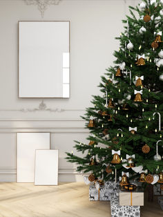 a christmas tree with presents under it in front of a white wall and wooden floor