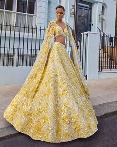 This lehenga set feature yellow three-dimensional highlighted with crystal, pearl and sequin on an ivory base. The waist of the blouse is scalloped and shows crystal drops. It is paired with four sided embroidered dupatta.From Seema Gujral's For the love of London collection. DELIVERY TIMEPlease allow 8-12 weeks for your outfit to arrive. FABRIC DETAILSNet Professional cleaning only. Yellow Floral Lehenga, Yellow Bridal Lehenga, Lehenga Yellow, Modern Lehenga, Sangeet Lehenga, Haldi Dress, Character Wardrobe, Haldi Outfit, Floral Lehenga