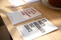 two books sitting on top of a wooden table next to a plate with cake in it