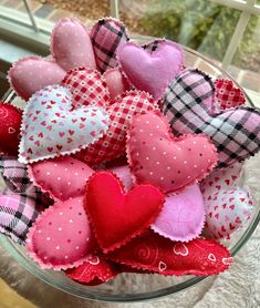 a glass bowl filled with lots of pink and red heart shaped decorations on top of a table