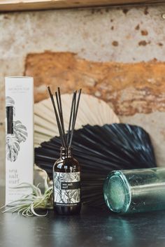 an empty bottle sitting on top of a table next to a candle and reed diffuser