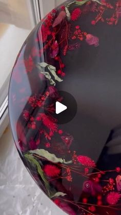 a glass bowl with red flowers painted on the outside and inside is shown in front of a window