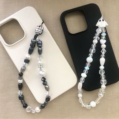 two cell phones are sitting next to each other on a table with beaded necklaces