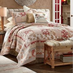 a bedroom with a bed covered in a red and white quilt next to a fireplace