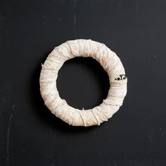 a piece of yarn wrapped around a white ring on a black surface with the eyeballs drawn on it