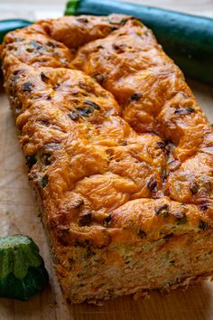 a piece of bread sitting on top of a wooden cutting board next to a green pepper