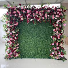 a green wall with pink and red flowers on it in the middle of a room