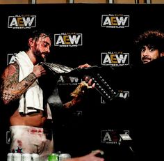 two men standing next to each other in front of a black backdrop with the words aew written on it