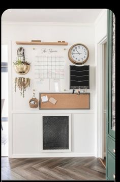 a white wall with a clock, calendar and other items on the wall next to it