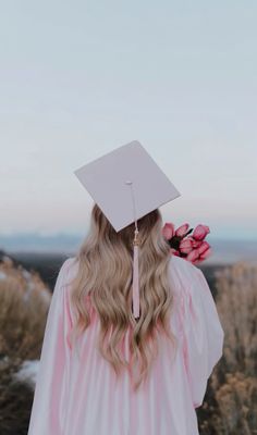 a woman wearing a graduation cap and gown with flowers in her hair looking at the sky