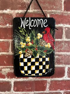 a welcome sign hanging on the side of a brick wall next to a red bird