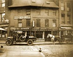 an old photo of a horse and buggy parked in front of a restaurant on the street