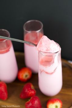 two glasses filled with pink liquid and strawberries on a plate next to each other