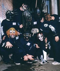 a group of people with masks on posing for a photo in front of a brick building