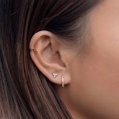 a woman wearing ear piercings with two small stones on the side of her ear